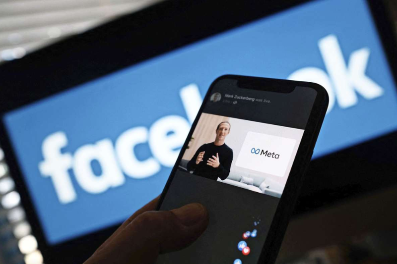 Mark Zuckerberg bei Meta Ankündigung auf Smartphone, dahinter Facebook Logo